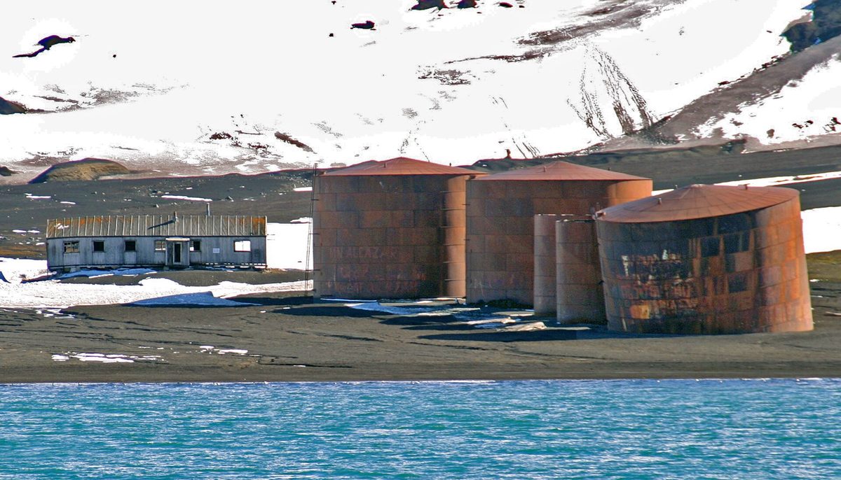 Volcanic black-sand shore and old whaling station ruins at Deception Island