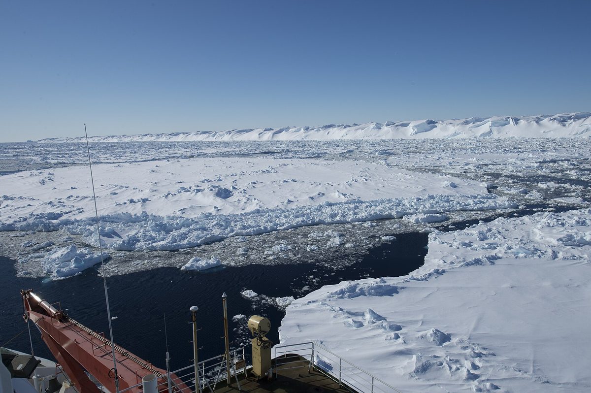 The bow of an expedition ship pushing through heavy pack ice in Antarctica