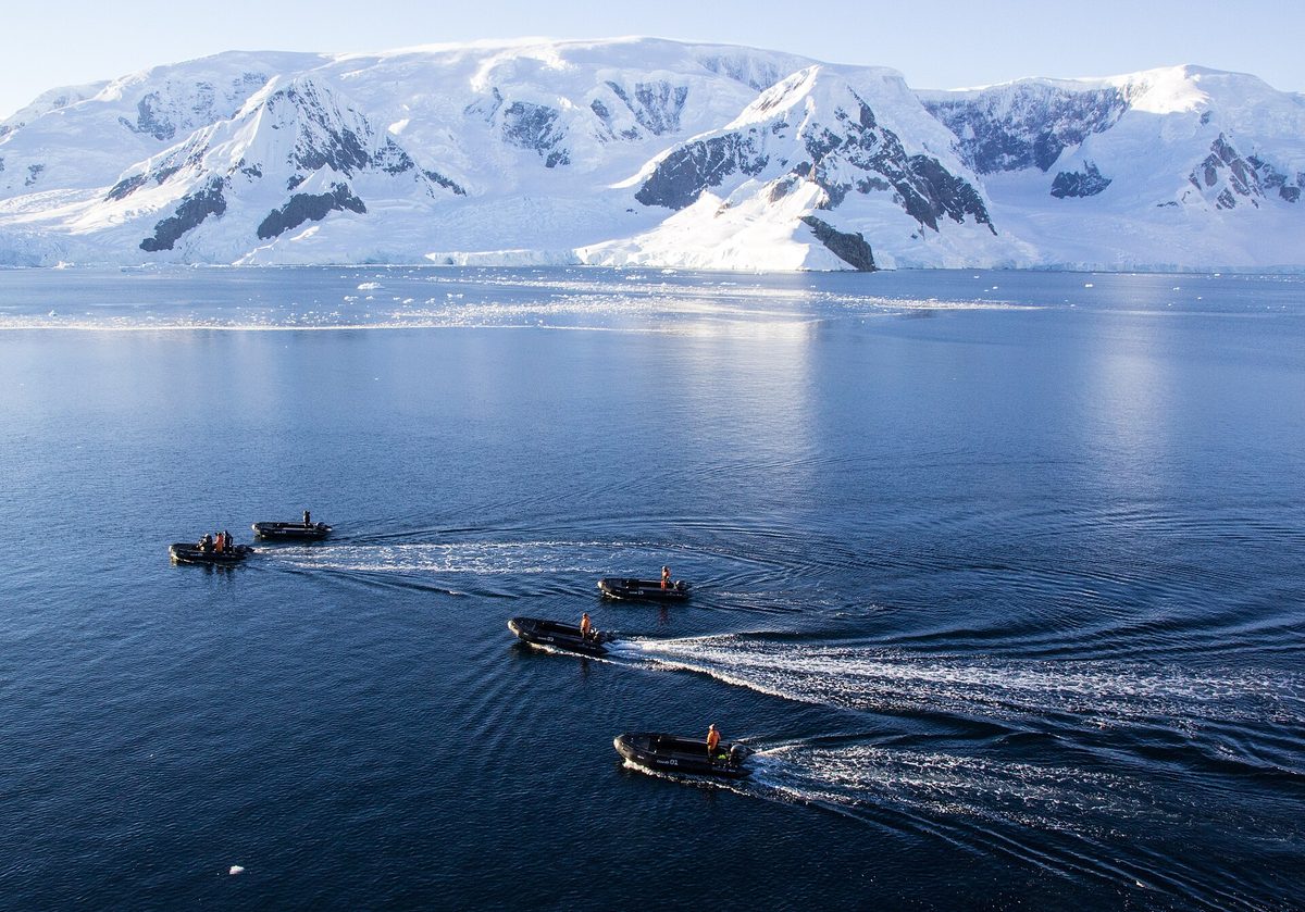 A Zodiac inflatable carrying expedition travellers past ice at Neko Harbour, Antarctica