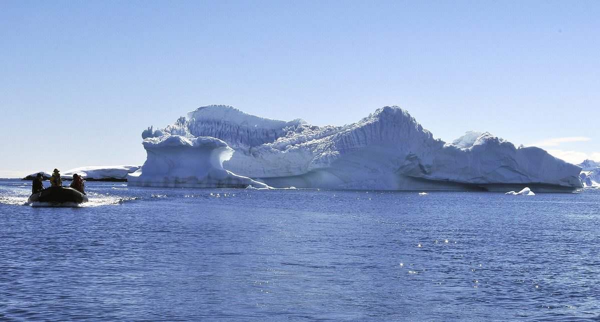 Expedition passengers in a Zodiac cruising past Antarctic ice