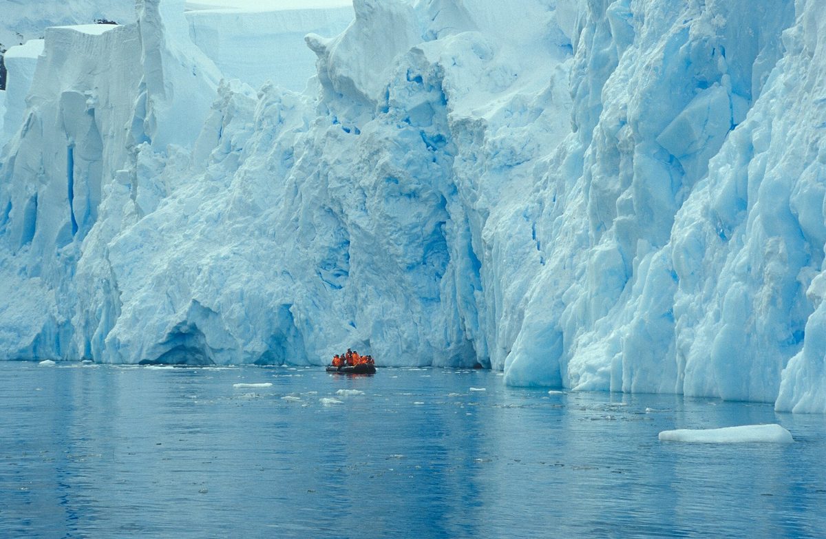 A Zodiac cruising beneath a glacier in Antarctica